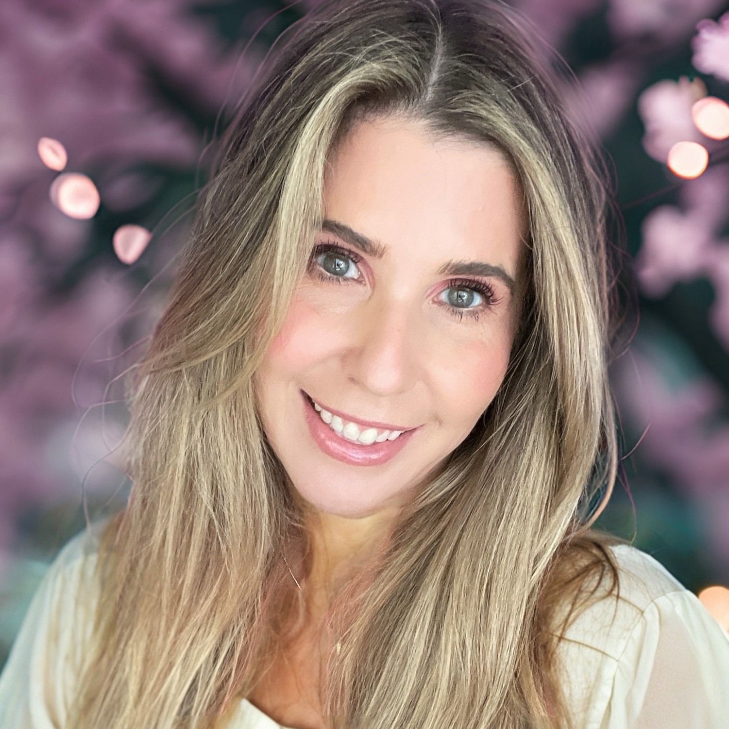 Portrait of a woman with brown hair on a flat gray background.